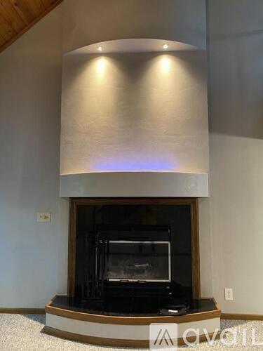 A modern fireplace with a wooden mantle and a shiny metal surround.