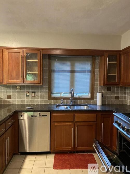 A kitchen with wooden cabinets and a stainless steel dishwasher.