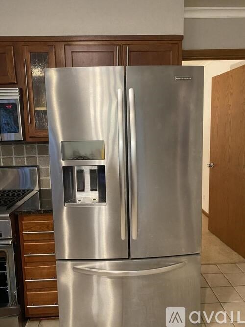 A stainless steel refrigerator with a water dispenser in the middle of the door.