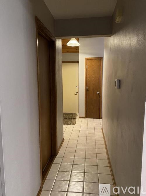 A hallway with a tiled floor and a wooden door.