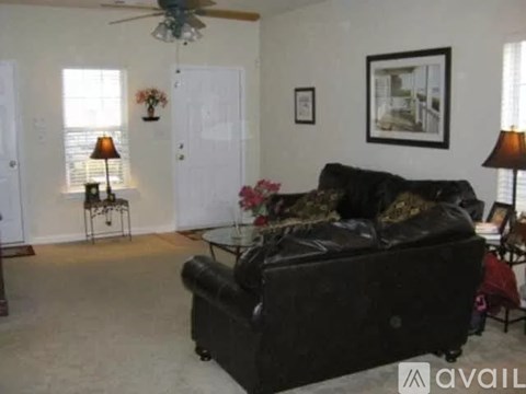 A living room with a black couch and a ceiling fan.
