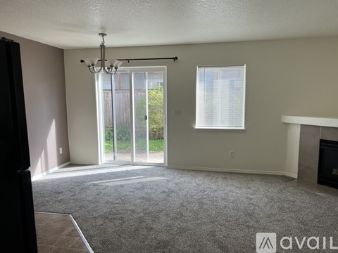 A living room with a grey carpet and a chandelier.