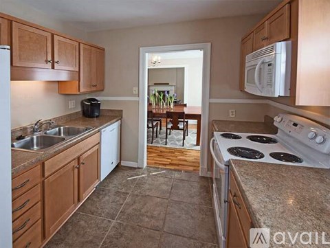 A kitchen with wooden cabinets and a white stove top oven.