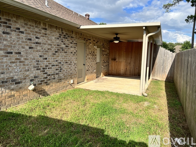 A backyard with a wooden fence and a covered patio area.