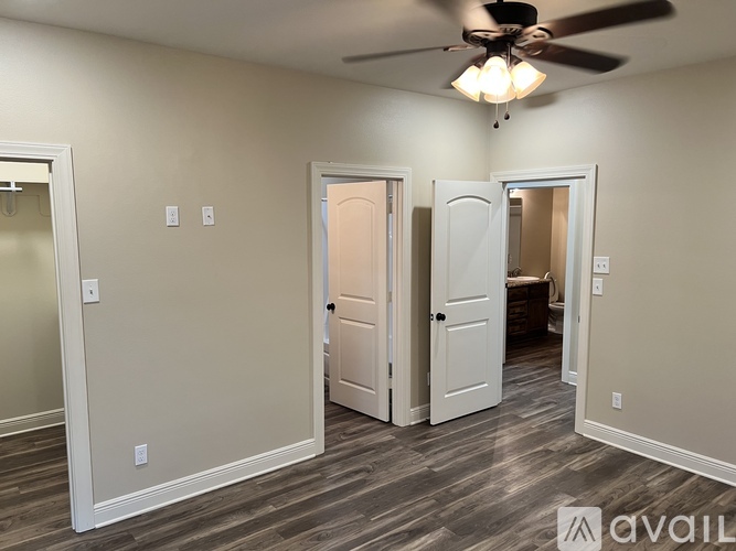 A room with a ceiling fan and three doors.