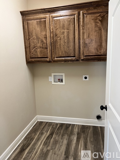 A wooden cabinet with a door is in the corner of a room.