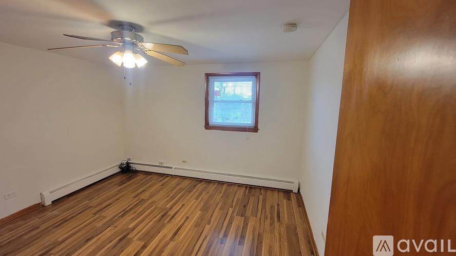 A room with wooden flooring and a ceiling fan with lights.