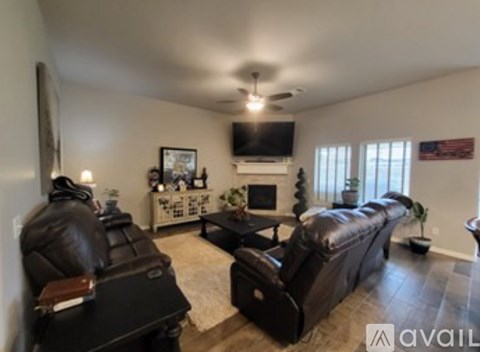 A living room with a black leather couch and a television.