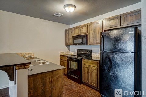 A kitchen with wooden cabinets and a black refrigerator.