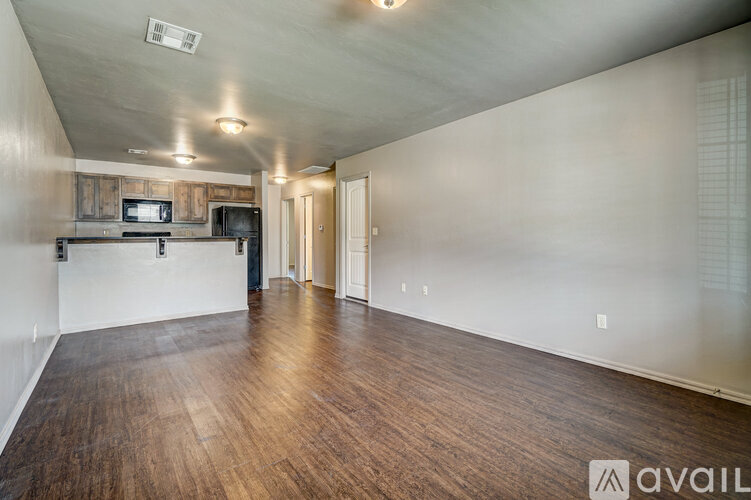 A room with wooden floors and a kitchenette in the corner.