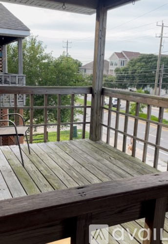 A wooden deck with a metal railing and a view of the street.