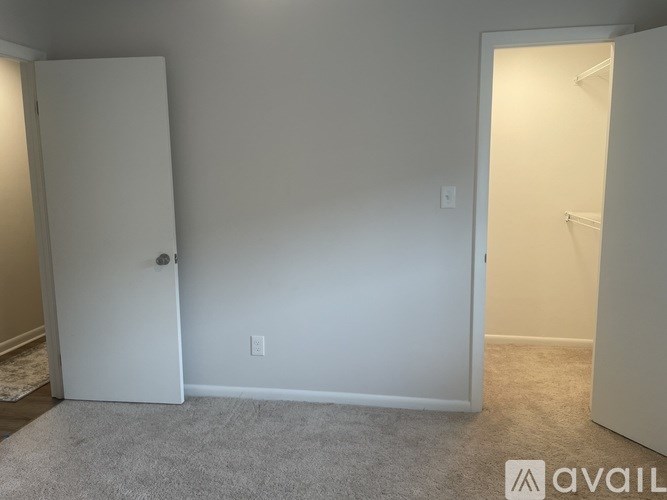 A room with a white door and a carpeted floor.