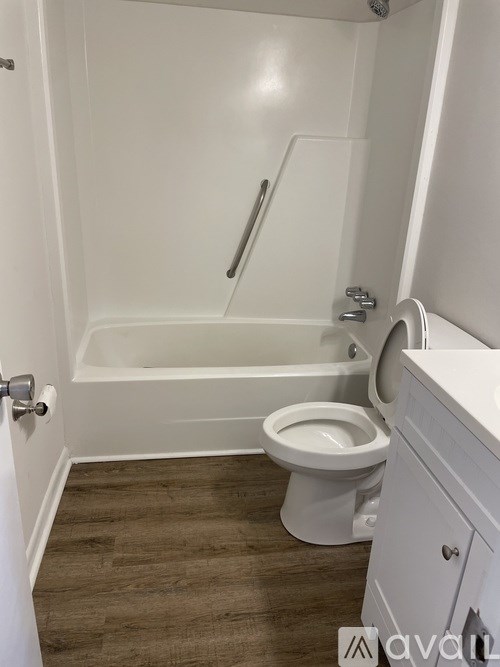 A white toilet sits next to a white bathtub in a small bathroom.