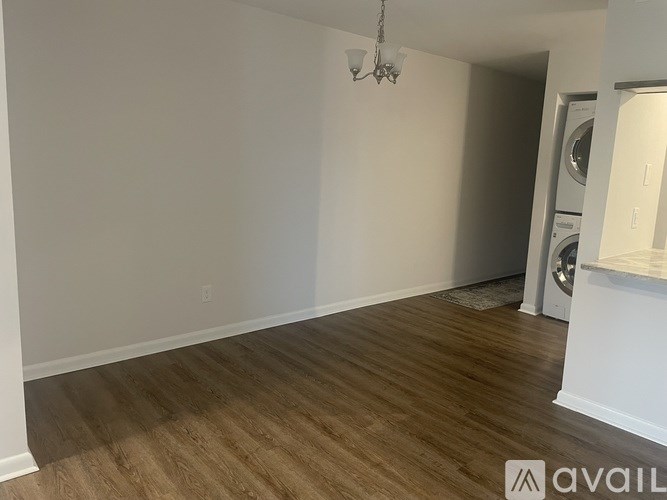 A room with wooden flooring and a washer and dryer in the corner.