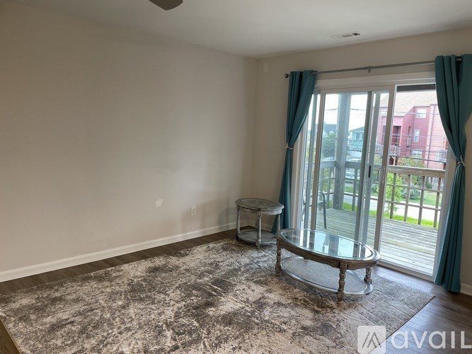 A room with a large rug and a glass table with a view of the outside.