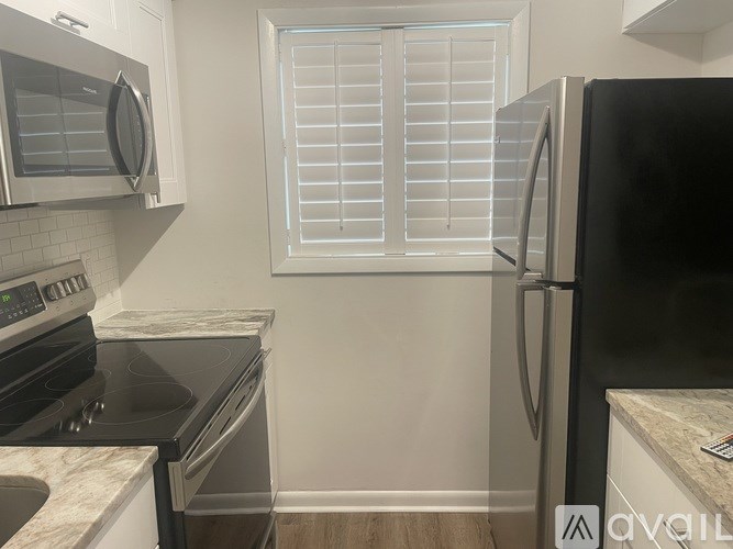A kitchen with a black refrigerator, stove, and microwave.