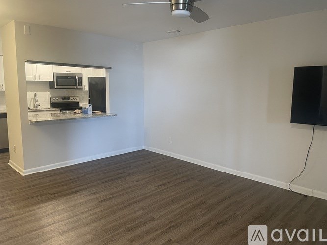 A room with a wooden floor and a wall-mounted television.
