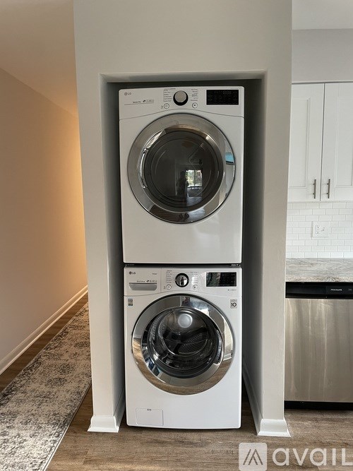 A white front load washing machine with a top load dryer in a small room.