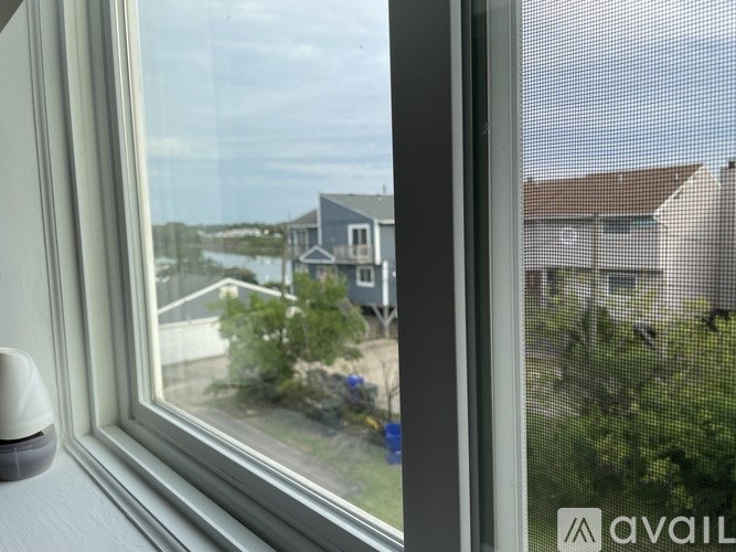 A window with a view of a house and a body of water.