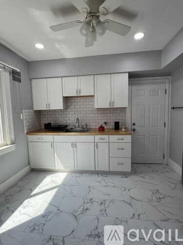 A kitchen with white cabinets and a marble floor.