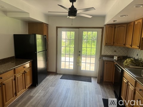 A kitchen with wooden cabinets and a black fridge.