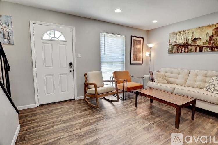 A living room with a white couch, a wooden rocking chair, and a wooden coffee table.
