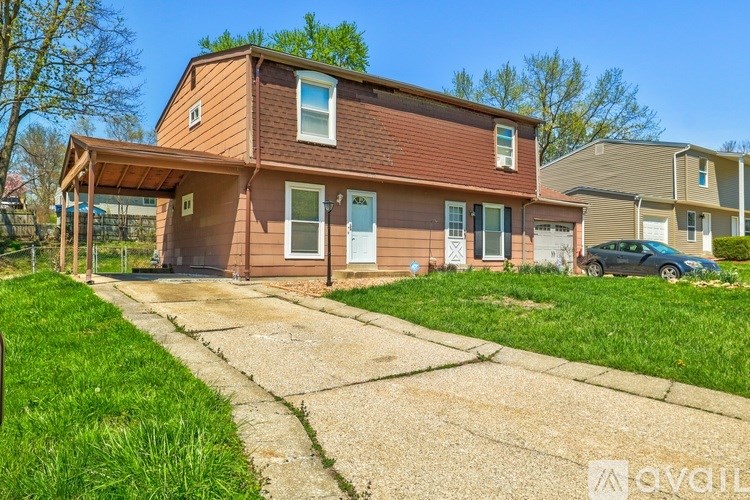 A house with a brown roof and a white door is surrounded by green grass.