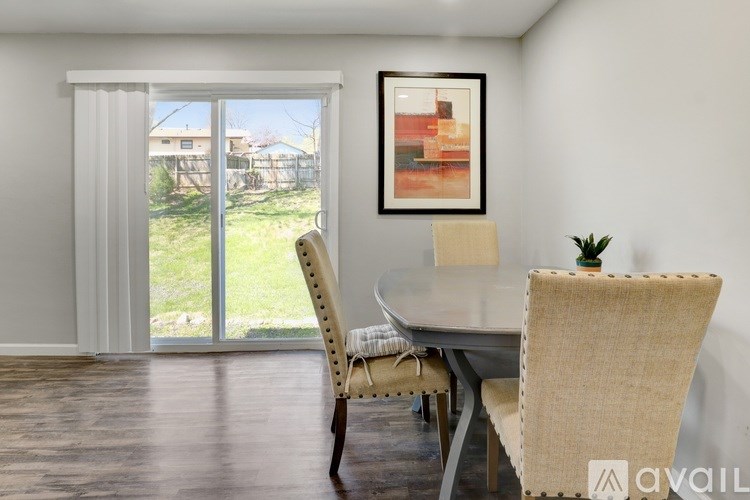 A dining room with a table and chairs and a painting on the wall.