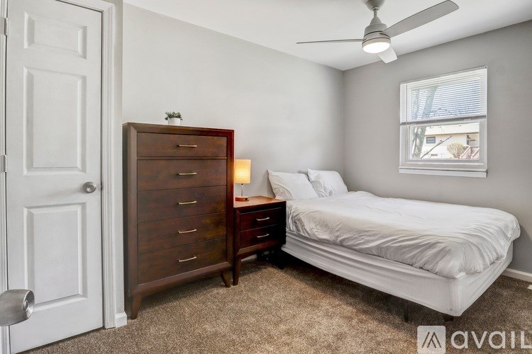 A bedroom with a bed, dresser, and window.