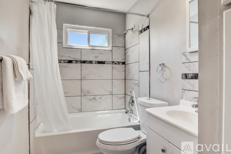 A bathroom with a white toilet, a white sink, and a white bathtub with a white shower curtain.