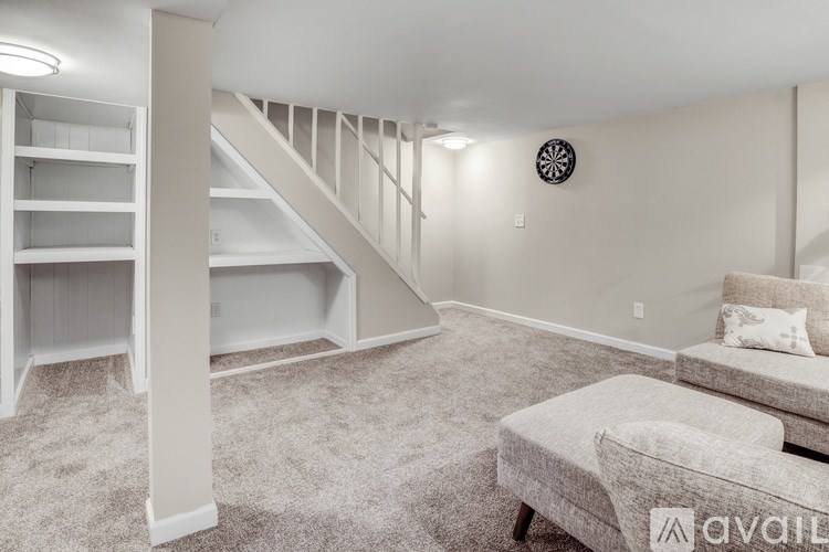 A living room with a grey couch and a white staircase.