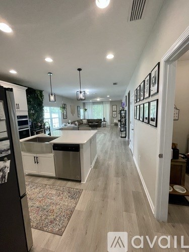 A kitchen with a refrigerator on the left and a dining area in the background.