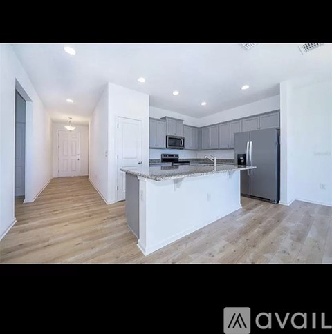 A kitchen with a white island and wooden floors.