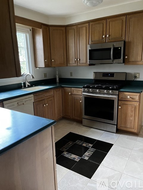 A kitchen with wooden cabinets and a black and white checkered mat on the floor.