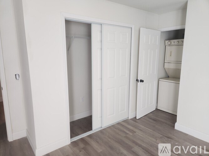 A white door is open to a room with a wooden floor.