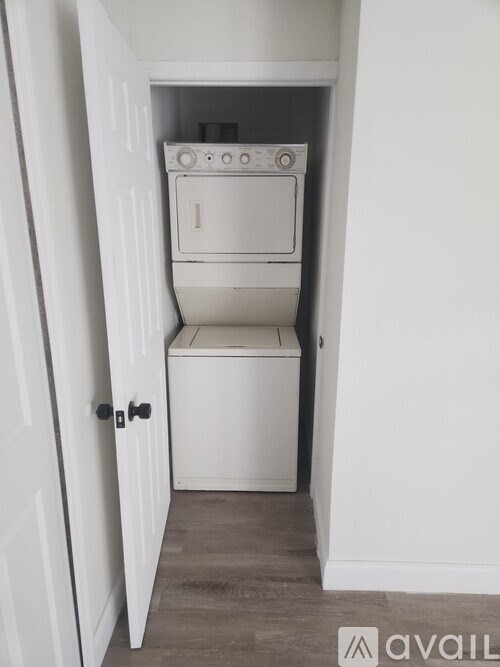 A white door opens to a small laundry room with a washer and dryer.