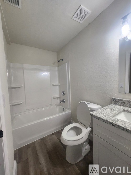 A white toilet in a bathroom with a white tub and sink.