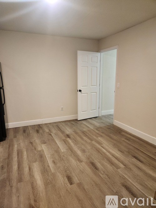 A room with a white door and wooden flooring.