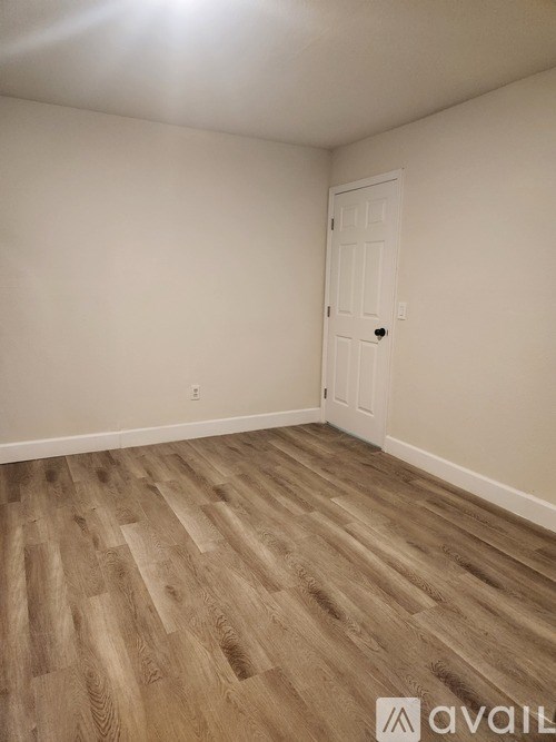 A room with a white door and wooden flooring.
