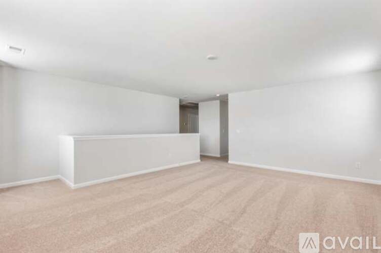 A spacious room with a carpeted floor and a door in the background.