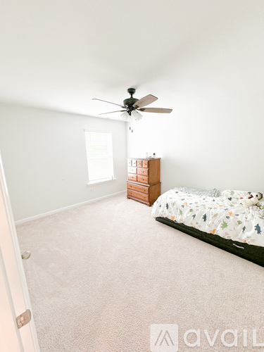 A bedroom with a bed, dresser, and ceiling fan.