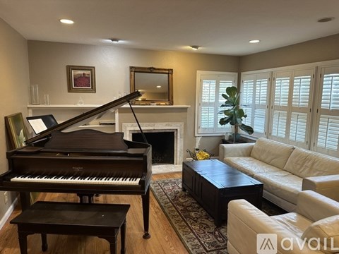 A grand piano sits in a living room with a couch and a coffee table.
