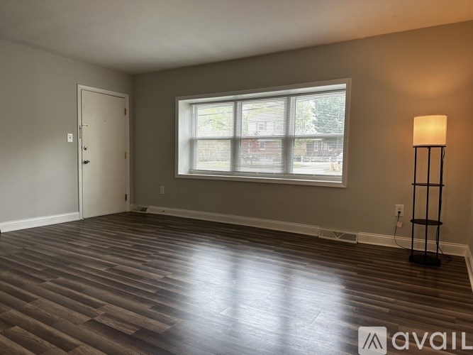 A room with wooden flooring and a window with blinds.