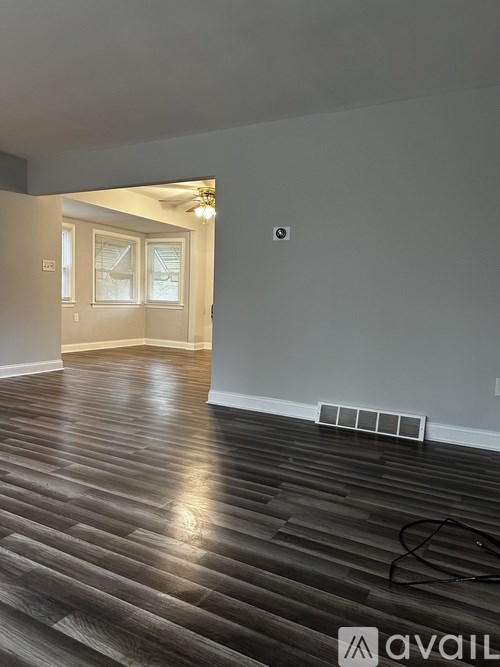 A room with wooden flooring and a doorway leading to another room.