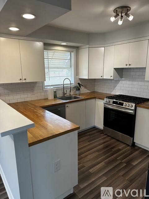 A kitchen with white cabinets and a wooden countertop.