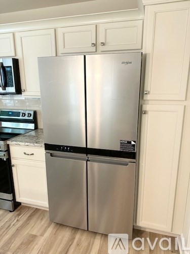 A stainless steel refrigerator with a black handle is in a kitchen.