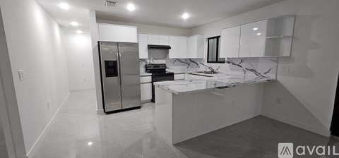 A kitchen with a marble countertop and a refrigerator.