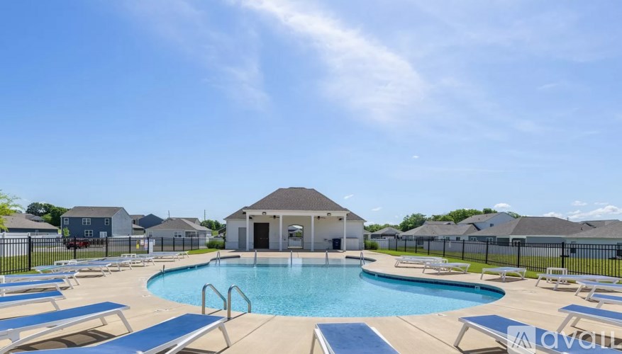 A pool with sun loungers and a pavilion in the distance.