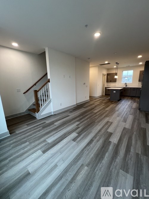 A spacious room with wooden flooring and a staircase.
