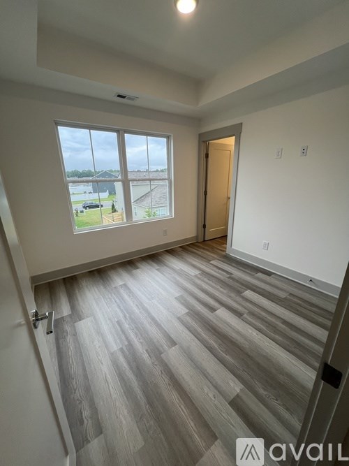 A room with a large window and a wooden floor.